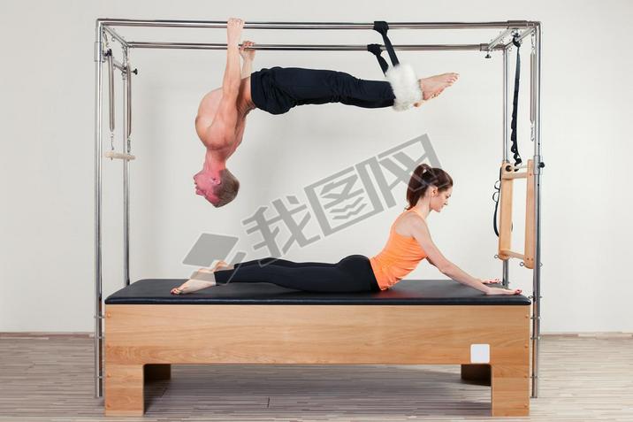 Pilates aerobic instructor woman and man in cadillac fitness exercise