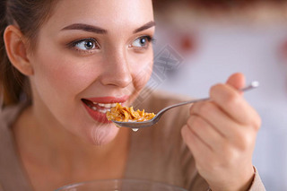 A young woman trying cereals in her kitchen