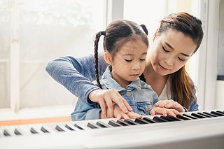 Asian young pianist teacher teaching girl kid student to play piano, music education concept