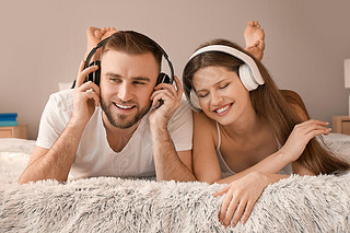 Happy young couple listening to music in bedroom