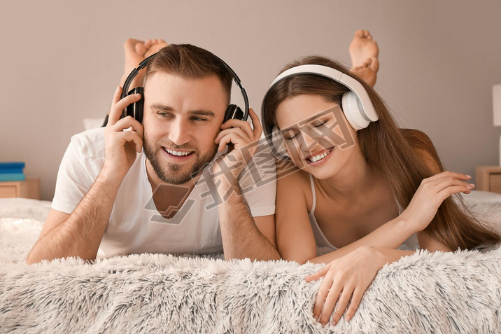 Happy young couple listening to music in bedroom
