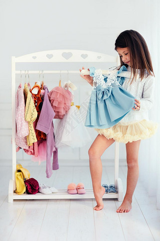 beautiful young girl, kid choosing party dress in wardrobe