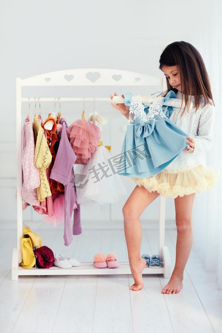 beautiful young girl, kid choosing party dress in wardrobe