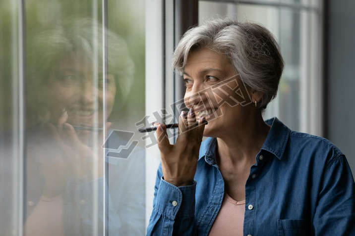 Happy middle aged elderly woman recording audio message.