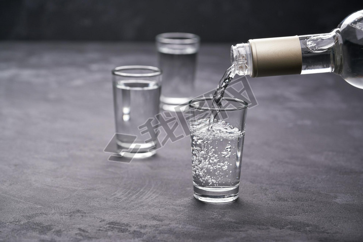 Pouring vodka into the glass on a black background, selective focus