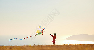 happy kid girl launches a kite at sunset outdoors