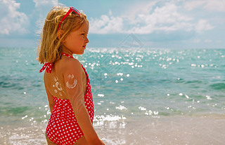 sun protection at beach- little girl with sunblock cream on shoulder