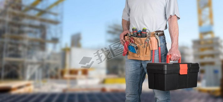 Building worker with tool belt on a construction site background