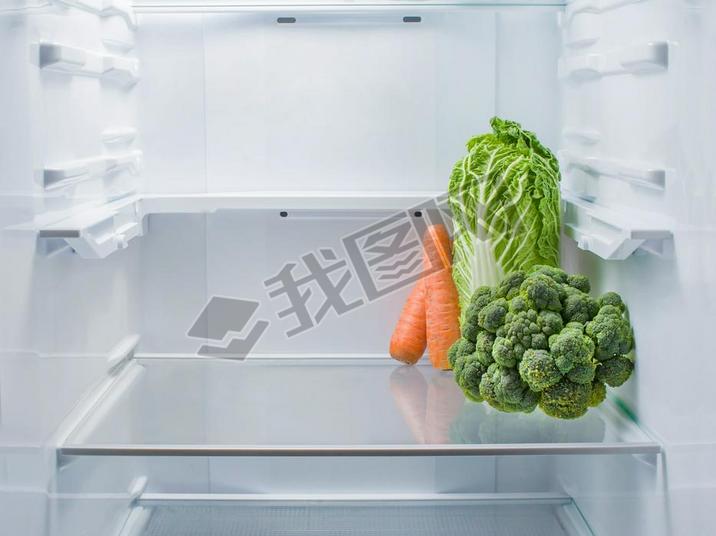 Fresh broccoli, Beijing cabbage and carrots in an empty refrigerator, copy space