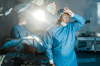 doctor in uniform and medical mask looking away in operating room