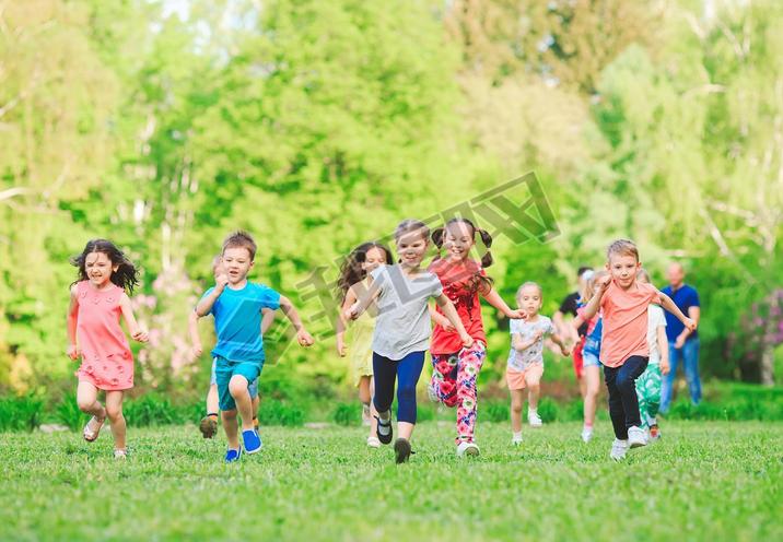 Many different kids, boys and girls running in the park on sunny summer day in casual clothes.