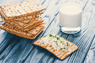 close-up view of crackers with cottage cheese and glass of milk on wooden table