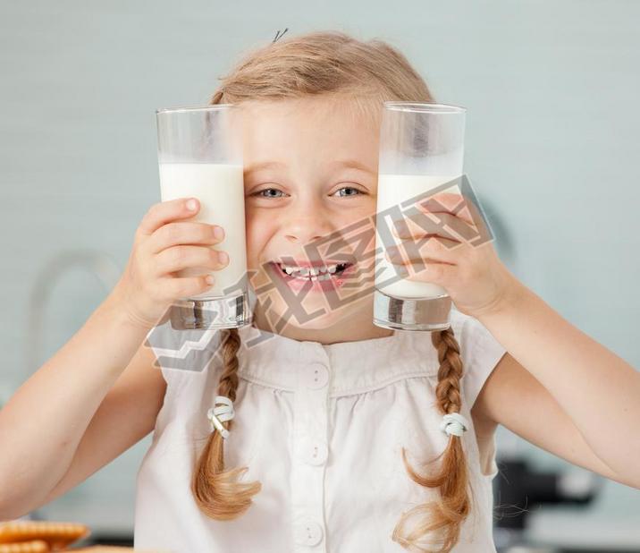 Child drinking milk at home. Happy little girl eating at home