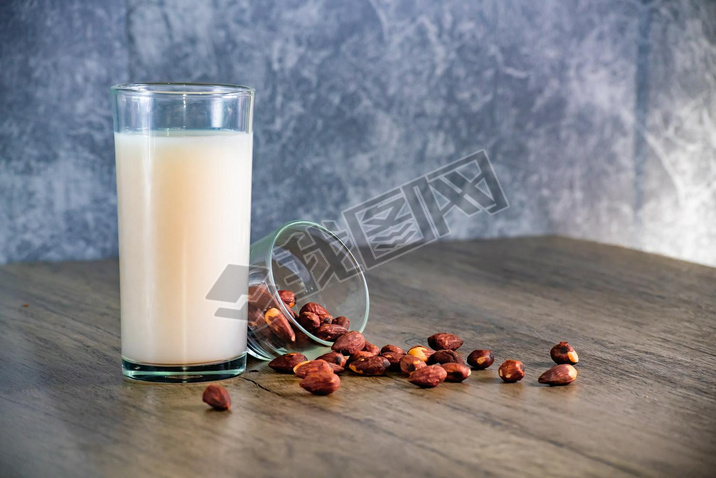 Almond milk with almond on a wooden table and background is bare cement walls