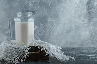 Glass jug of milk in wooden box with burlap