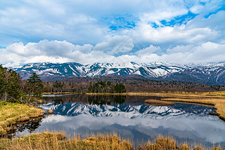 Beautiful lake reflecting blue sky like a mirror, rolling mountain range and woodland in the backgro