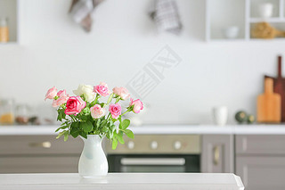 Beautiful rose flowers in vase on table in kitchen