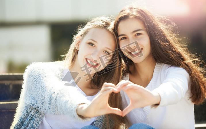 Two Teenagers Holding Hands in Shape of Heart