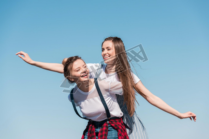 iling young woman doing piggyback ride to female friend 