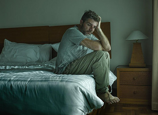 dramatic lifestyle portrait of handsome guy sitting on bed feeli