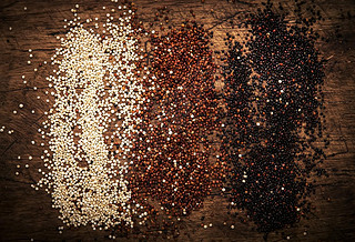 Quinoa set. Black, white and red raw quinoa grains in bowls, groats assorted, wooden rustic kitchen