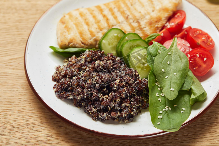 close up view of cooked quinoa with grilled chicken breast and vegetables on white plate