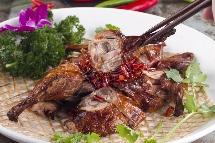 Roast pigeon with dry red pepper in a white dish