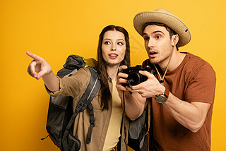 couple of shocked tourists with photo camera pointing on yellow