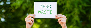 Horizontal crop of man holding card with zero waste lettering outdoors, ecology concept