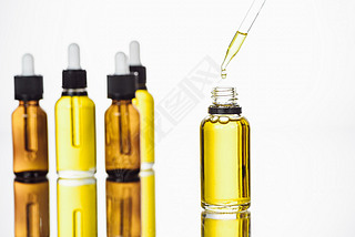 bottles and pipette with natural serum on surface with reflection isolated on white