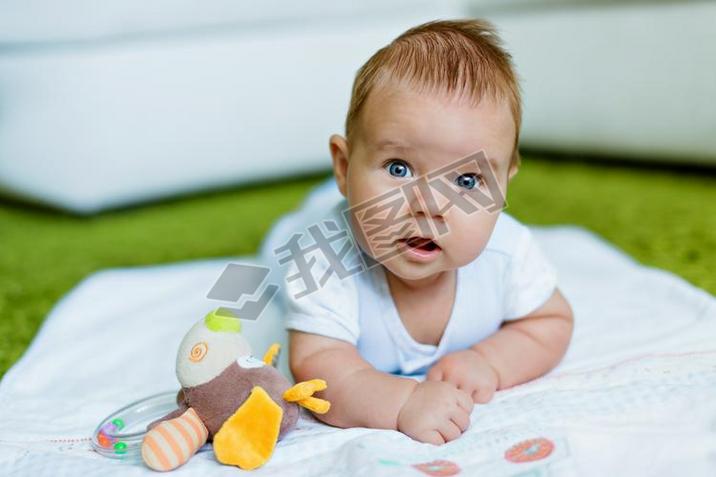 Blue-eyed little boy leans on the handle lying on the floor  of the house