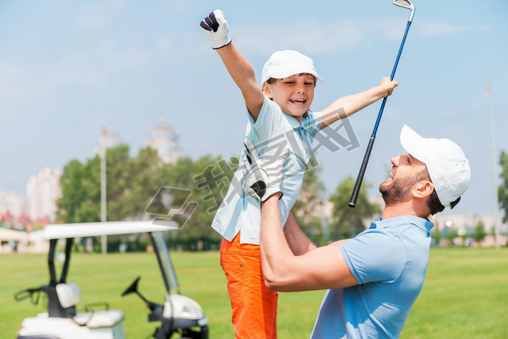 man picking up his son on golf course