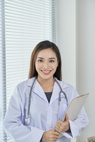 Young doctor or medic with clipboard and stethoscope standing on white background