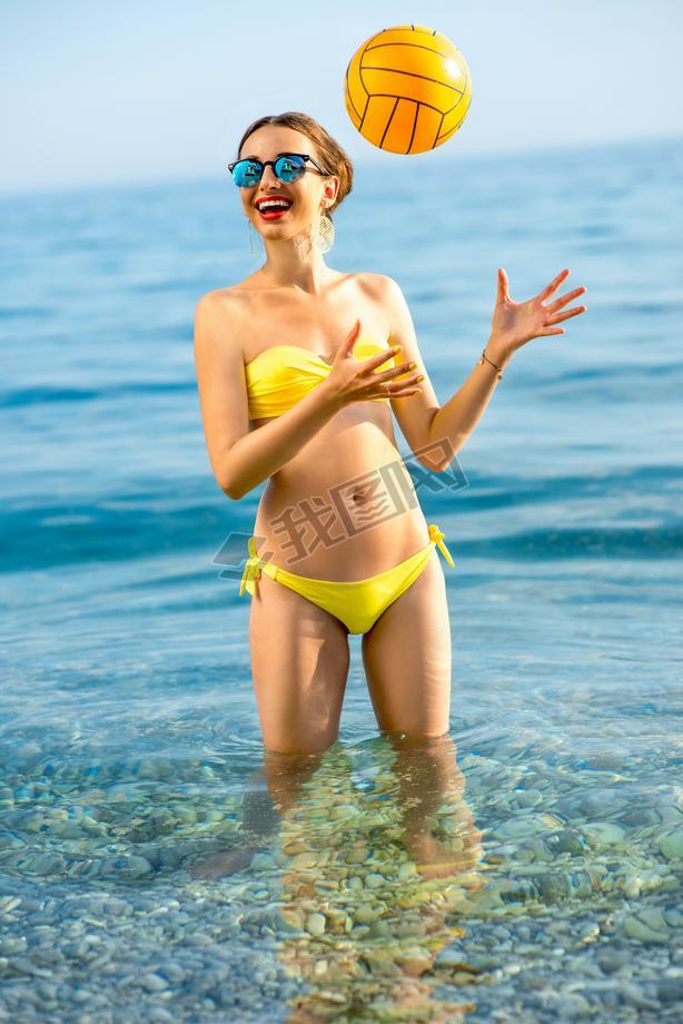 Woman with yellow ball in the sea