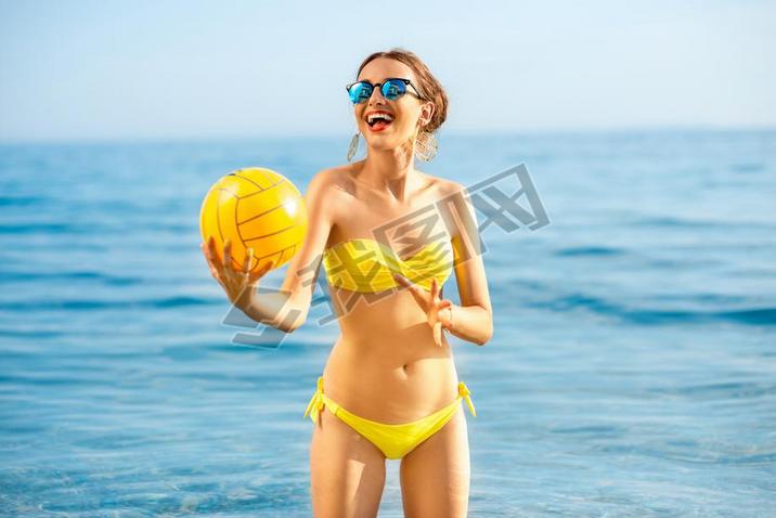 Woman with yellow ball in the sea