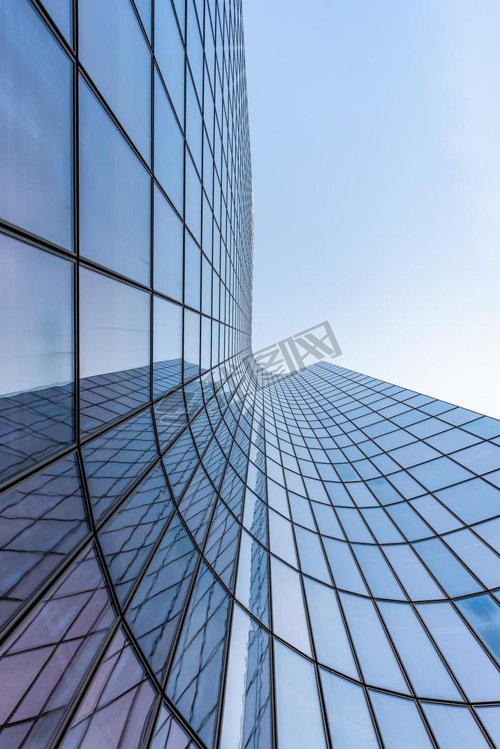 Blue curved glass skyscraper facade against sky