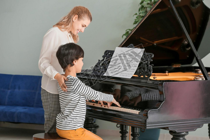 Private music teacher giving piano lessons to little boy