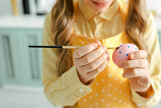 cropped view of kid painting easter egg with paintbrush at home