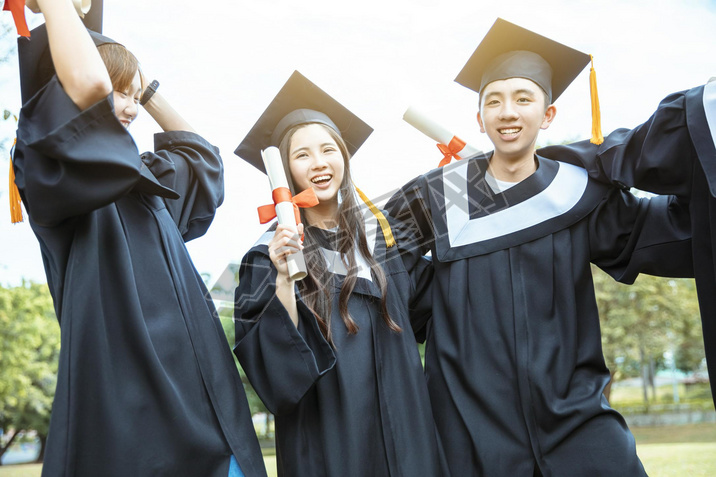 happy  students in graduation gowns holding diplomas on university campus