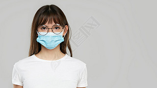 Asian woman feeling unwell and wearing face protective mask on grey studio background. Copy space fo