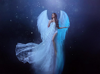幻想中的女天使带着白色的大鸟翅膀在空中翱翔。飘浮中的鬼女孩飞了。漆黑的夜晚背景，神奇的光芒。身着白衣的女神，挥动着的面料.