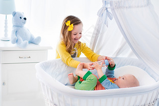 Little girl giving baby brother bottle with milk