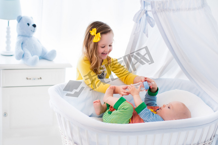 Little girl giving baby brother bottle with milk