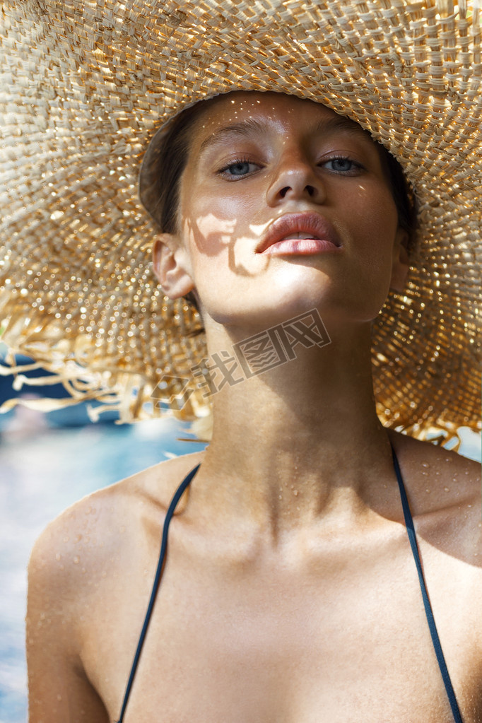 Woman in hat and black stylish swimsuit poses near swimming pool enjoying sun. Phuket island, Thaila
