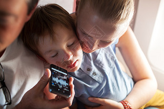 Child sleeping with music on cell phone in plane