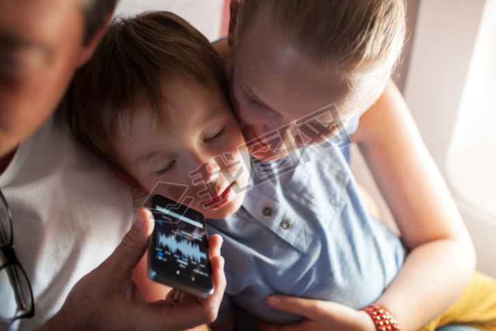 Child sleeping with music on cell phone in plane