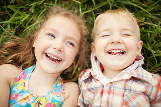 Top view of two kids brother and sister lying on grass