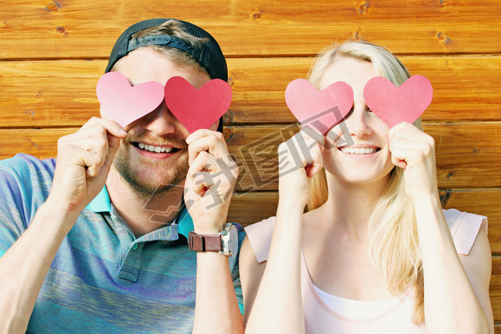 fall in love concept - young couple holding paper hearts over ey