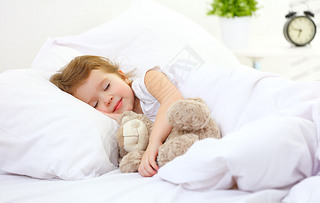 child little girl sleeps in the bed with teddy bear