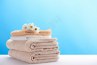 close-up view of beautiful chamomiles on pile of clean soft towels on blue